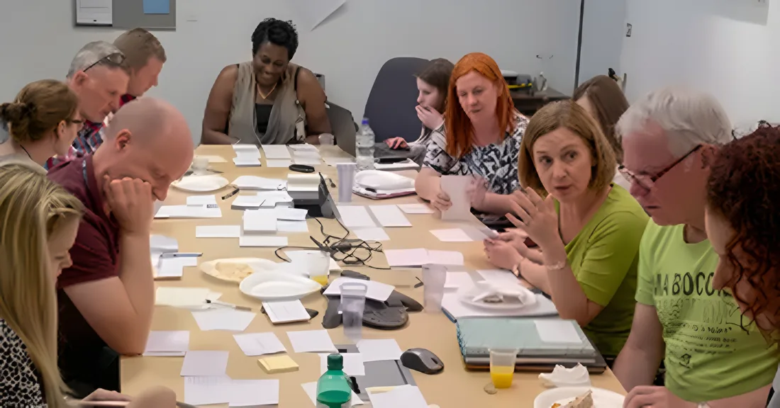 A co-design workshop: a client team around a table covered in cards and sticky notes